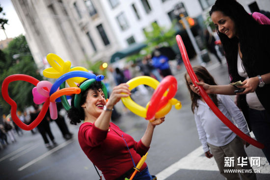 6月14日，在美國紐約曼哈頓第五大道，一位藝人為遊客製作氣球帽。新華社記者申宏攝