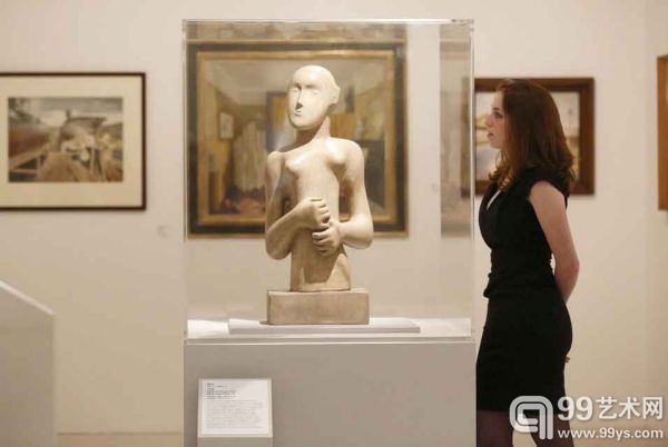 在皇家藝術學院呈現的紀念成立175週年的展覽現場，一位美術館助理正在觀賞亨利·摩爾1931年的雕塑作品《女孩兒》